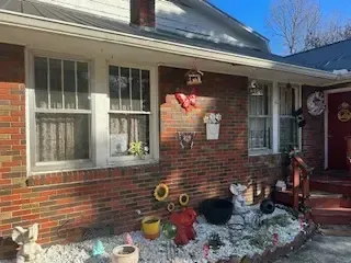 A brick house with a christmas decoration on the front porch.