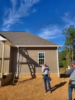 Two men are standing in front of a house under construction.