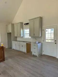 A kitchen with white cabinets , a sink , and a window.