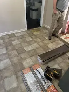 A man is standing on a tiled floor in a room.