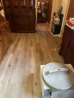 A kitchen with hardwood floors and a pot on the floor.