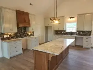 A kitchen with white cabinets and a large island in the middle.