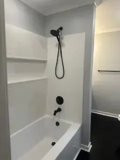 A bathroom with a bathtub and a shower head.
