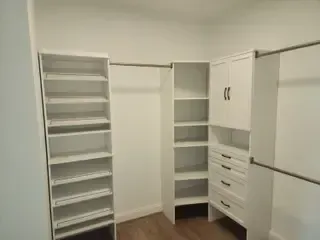 A walk in closet with lots of shelves and drawers.