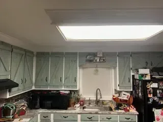 A kitchen with a sink , refrigerator , microwave , and cabinets.
