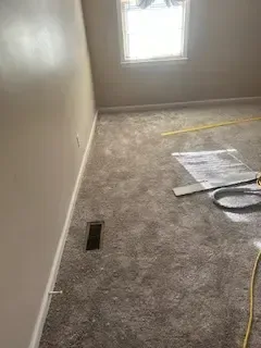 A room with a carpeted floor and a window.