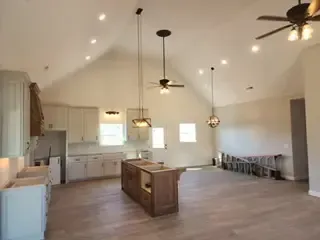 There is a ceiling fan in the kitchen and a large island in the middle of the room.