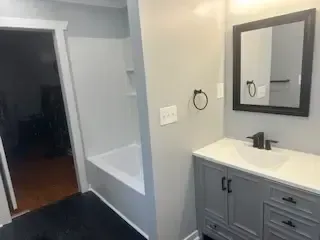 A bathroom with a sink , mirror and bathtub.