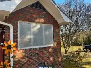 A brick house with a window covered in plastic.