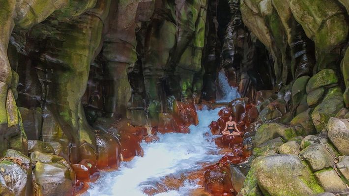 Rushing water cascades through a rock-walled cavern, with one person visible in a raft.