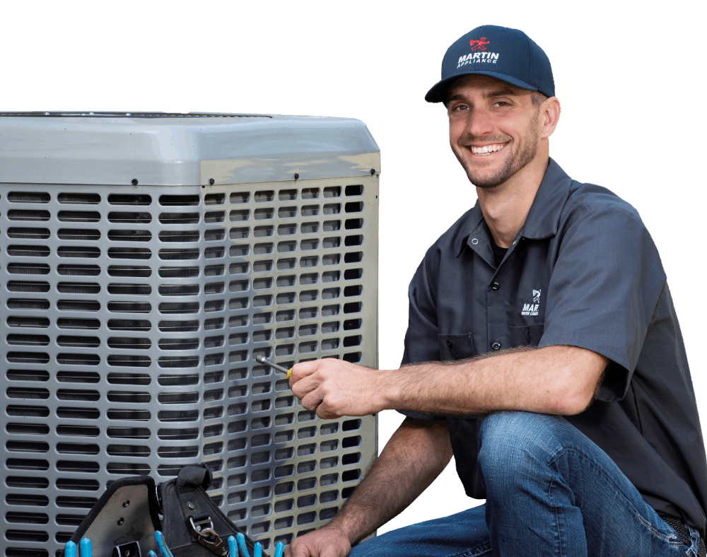 A man is kneeling down next to an air conditioner while working on it.