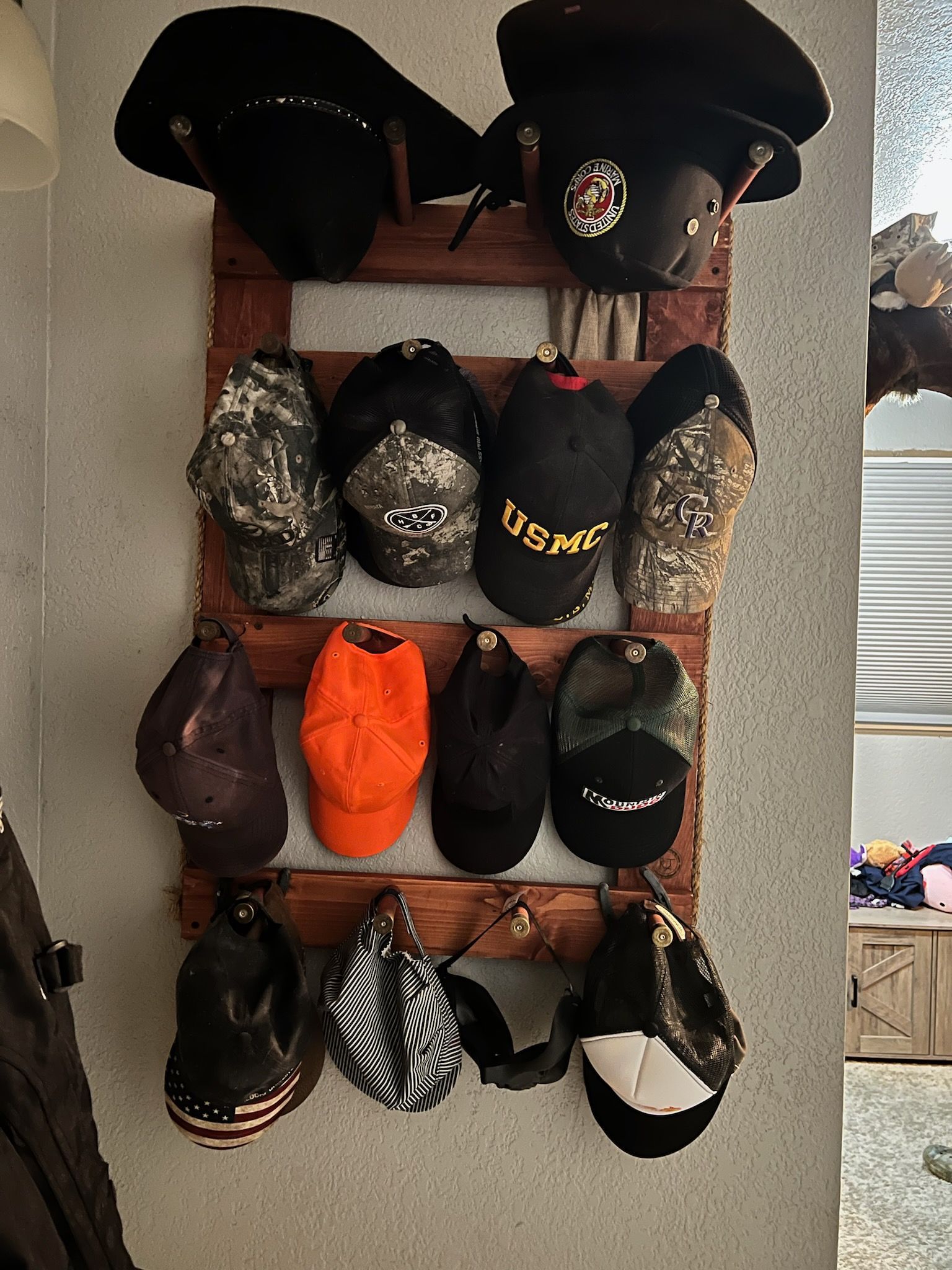 Collection of hats displayed on a wooden rack, various colors and styles.