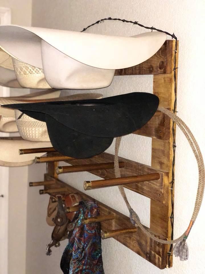 Rustic wooden hat rack with hats and accessories, mounted on a white wall.