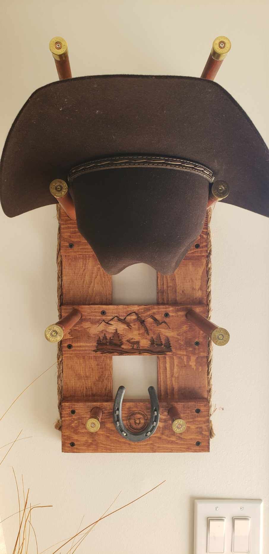 Cowboy hat on a wooden hat rack with shotgun shells as pegs and a horseshoe detail.