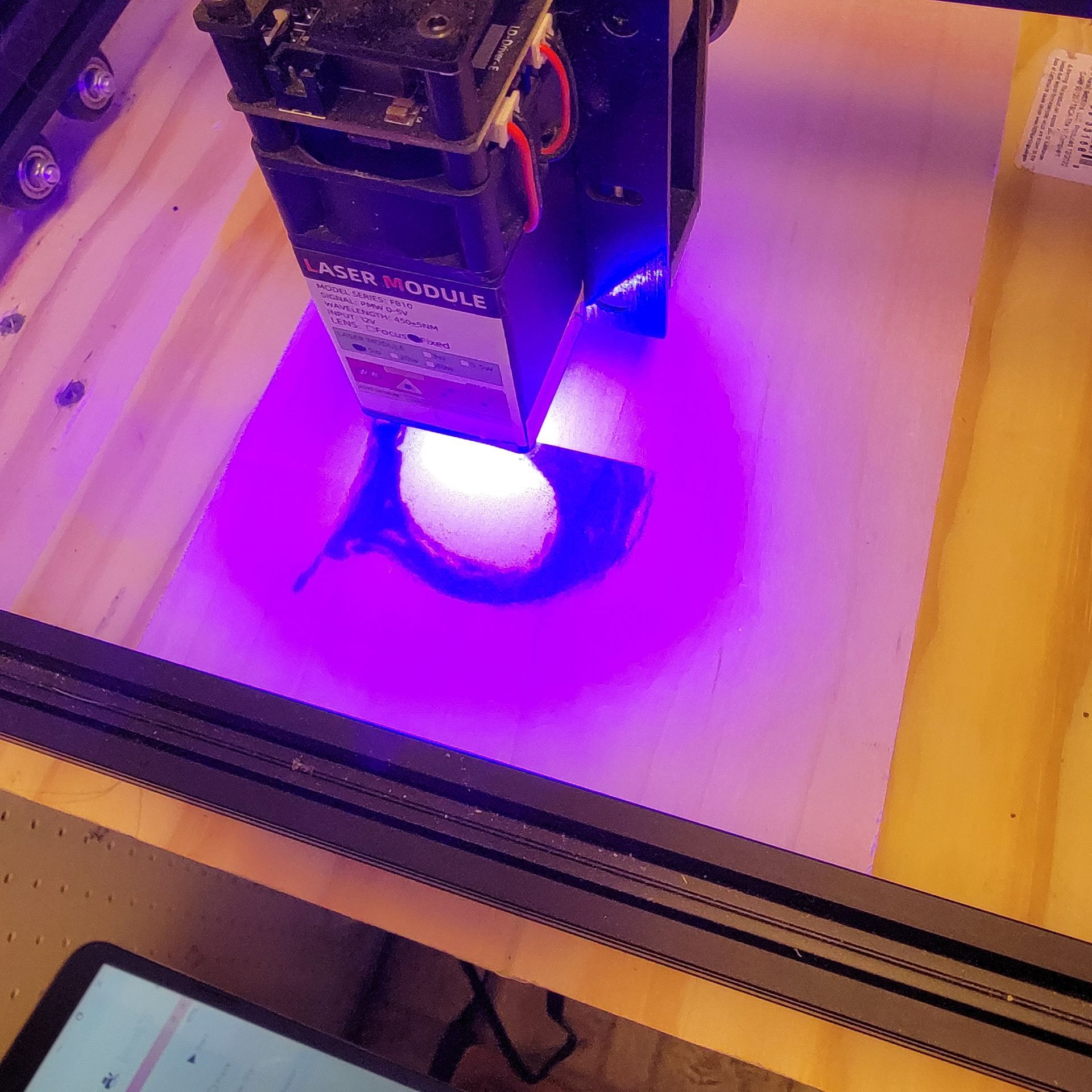 Laser cutter engraving a circular pattern on wood.