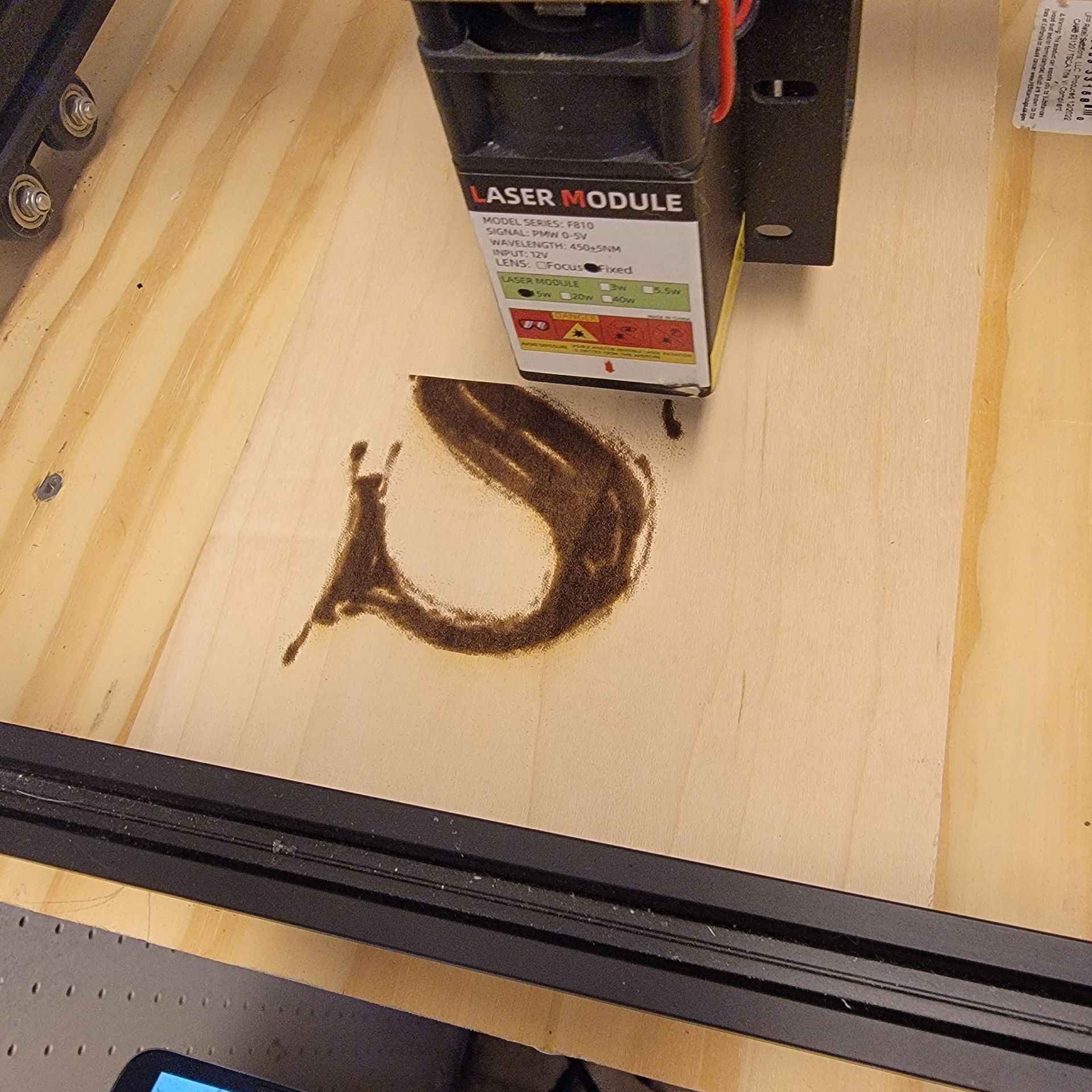 Laser engraver burning a slug image onto a wooden surface.