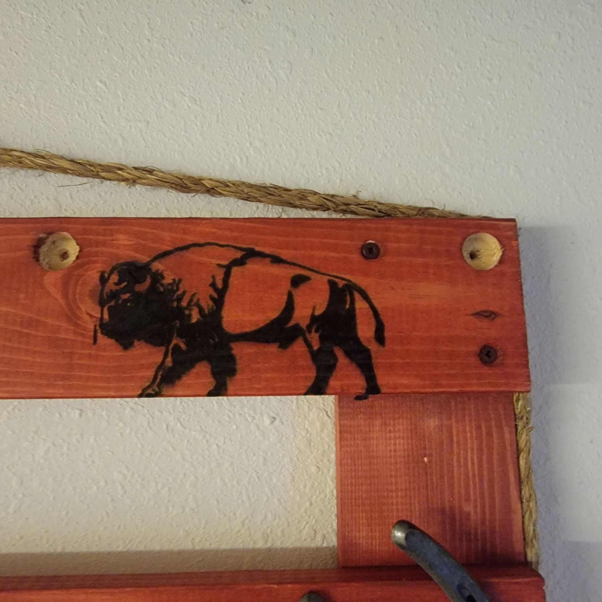 Wooden wall decor with a bison silhouette; rope, wood, and horseshoe accents.
