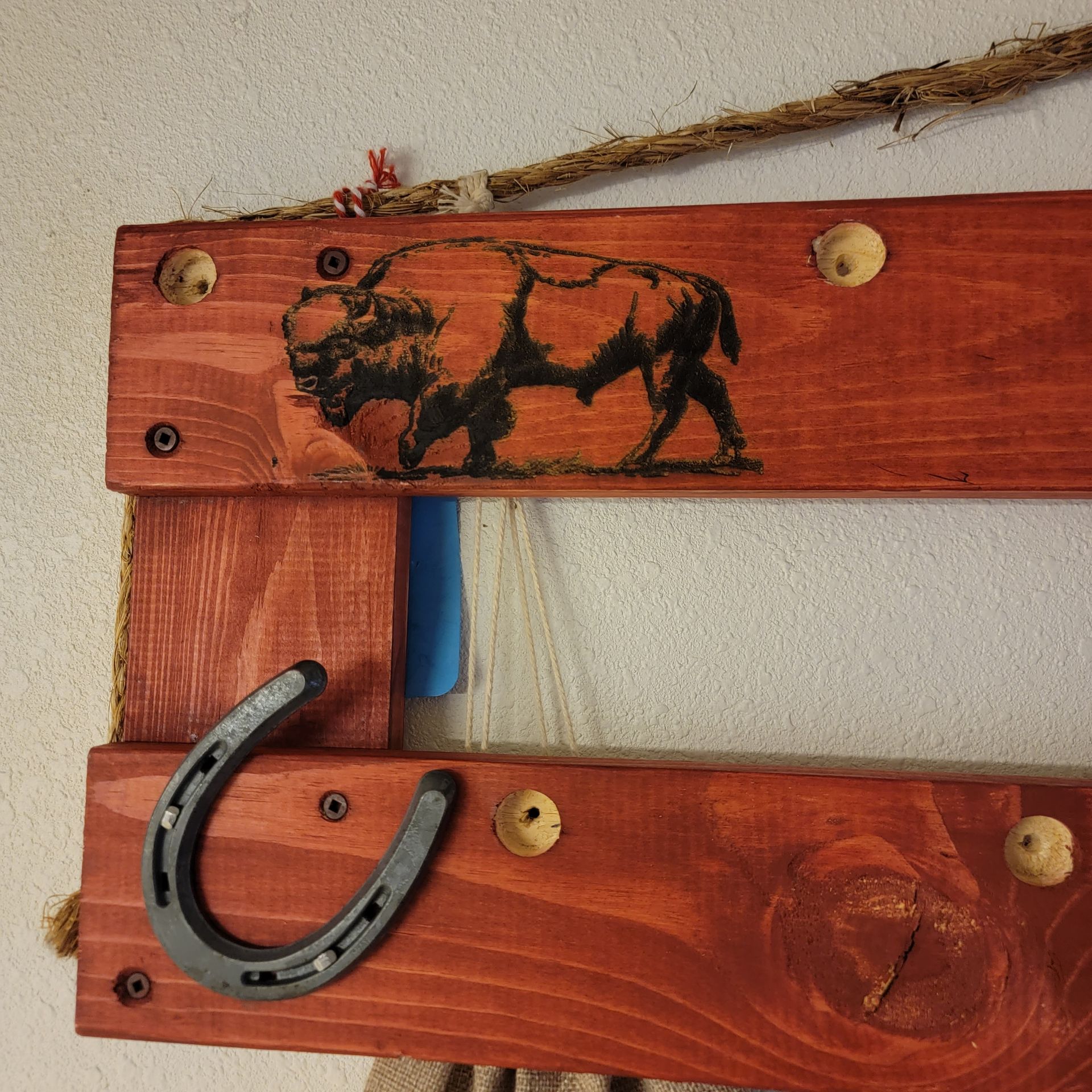 Wooden wall rack with a bison image and horseshoe hook.
