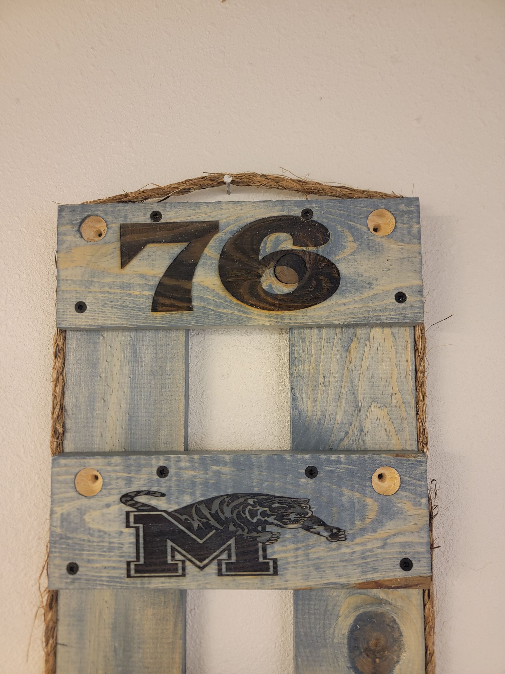Wooden sign with the number 76, a tiger logo, and the letter 