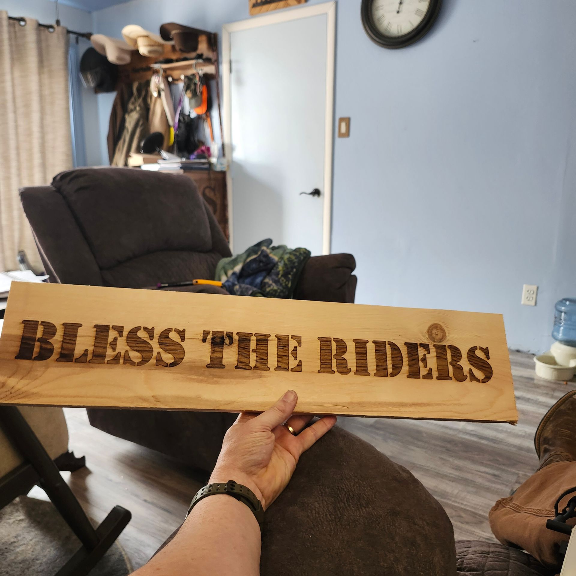 Hand holding a wooden sign that reads 