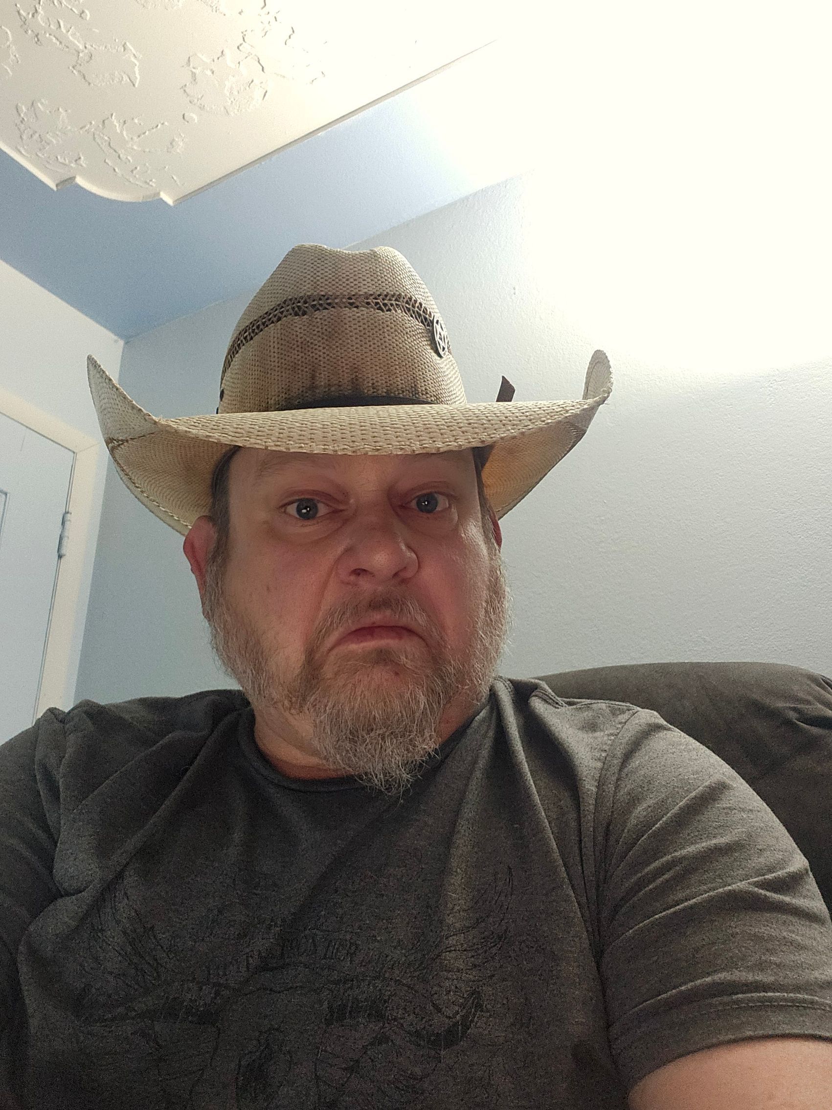 Man in straw cowboy hat, looking directly at the camera with a neutral expression.