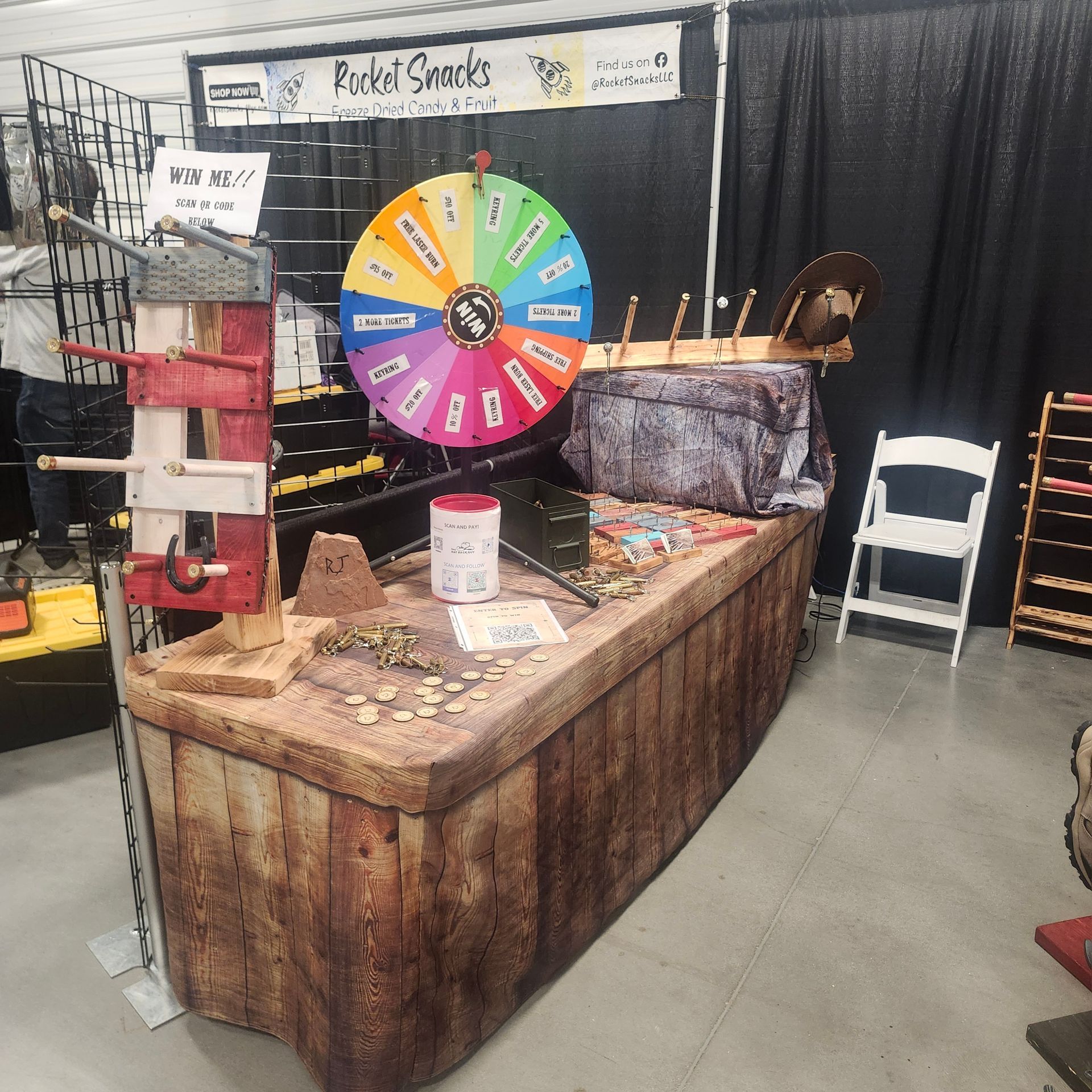 Booth with a wooden boat-shaped counter. A prize wheel and jar are on top.