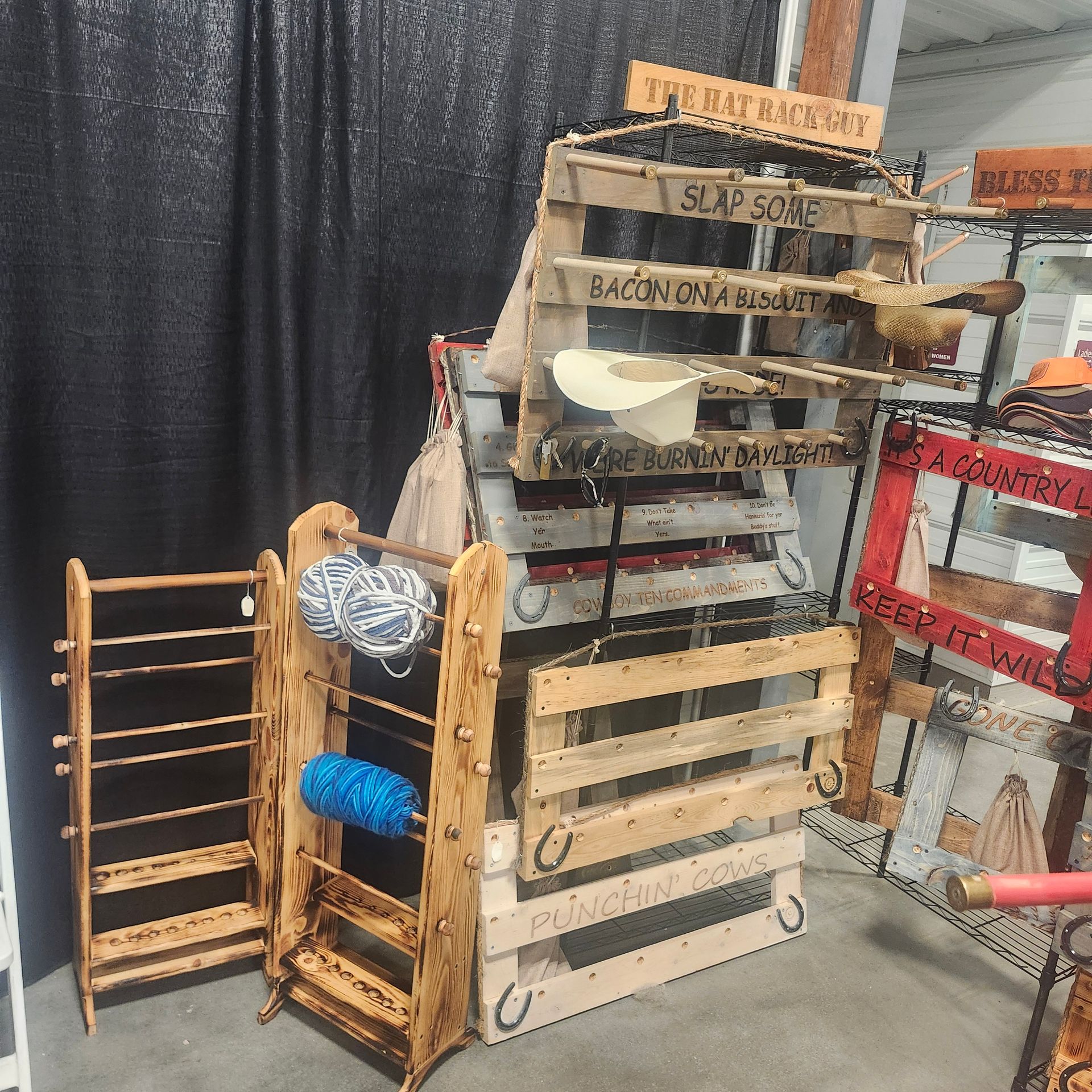 Wooden display with yarn, signs, and a cowboy hat. Black curtain background.
