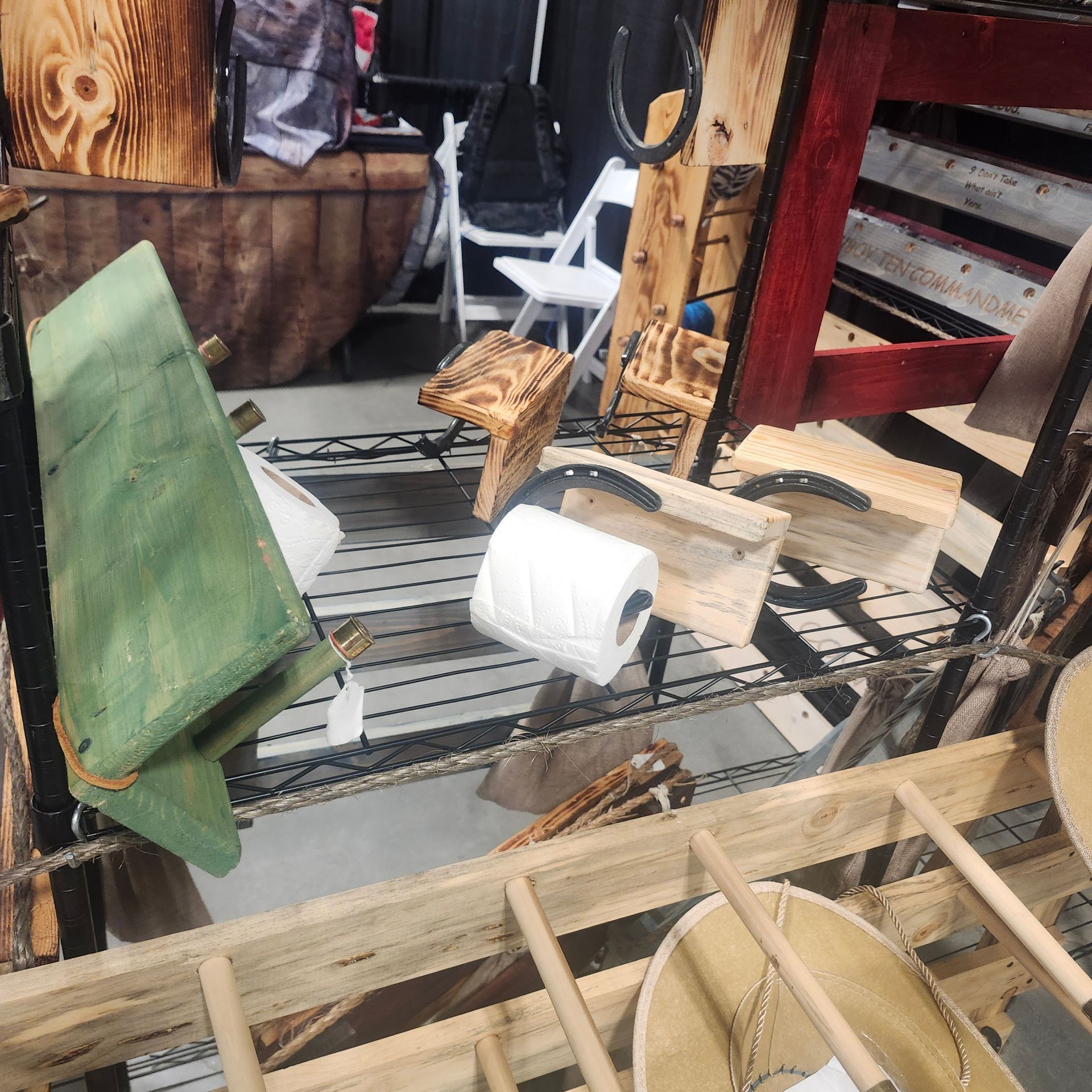 Wooden crafts on display at a craft fair, including chairs, shelves, and toilet paper holders.