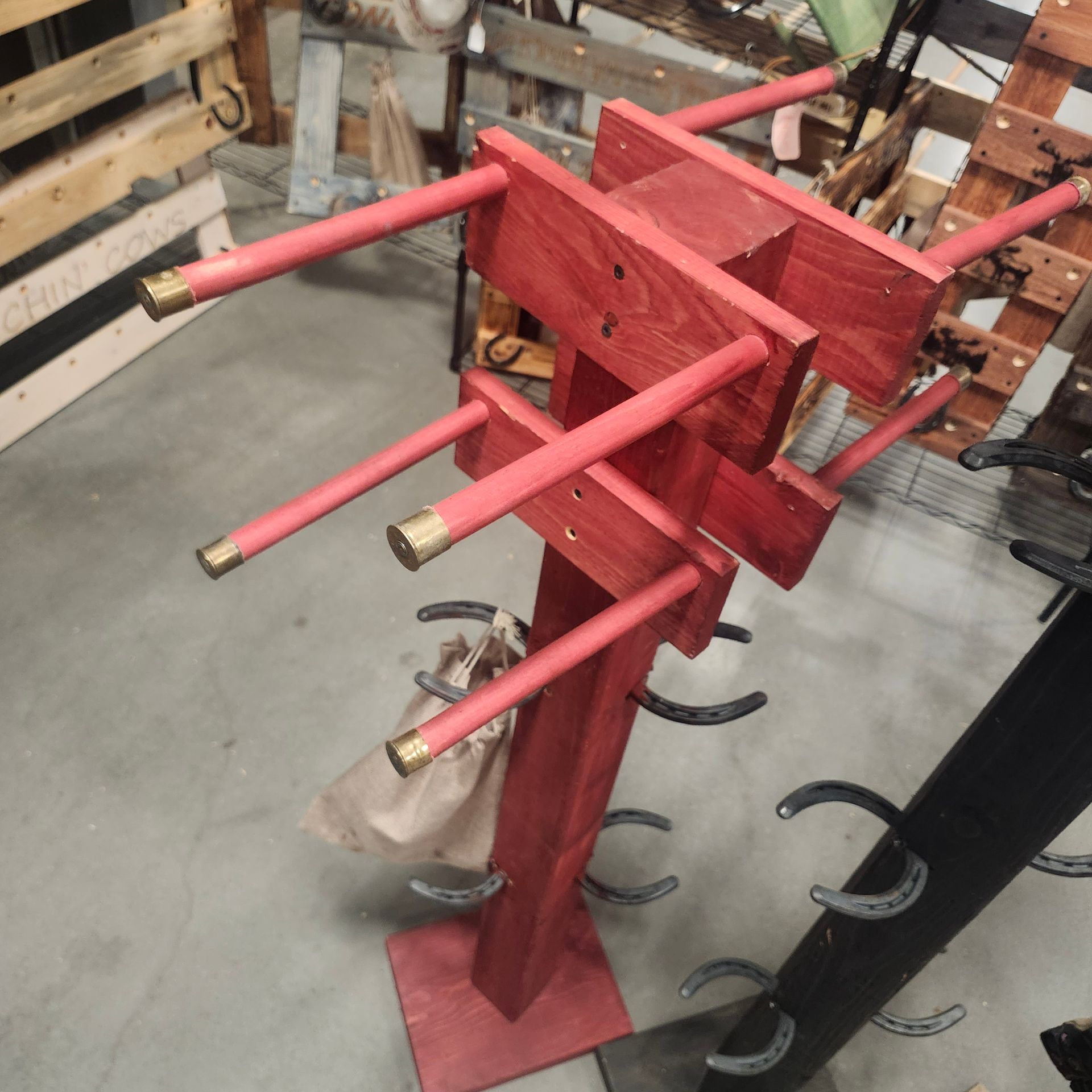 Red wooden display stand with dowels, metal hooks, and a hanging bag.