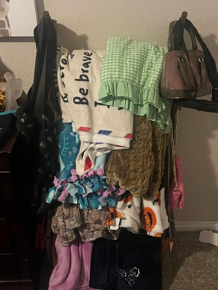 Clothes rack with garments: white, green, brown, and blue clothing items with various accessories hanging.