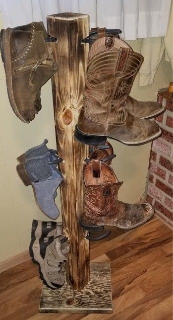 A wooden boot rack holding four pairs of boots, set against a room interior.