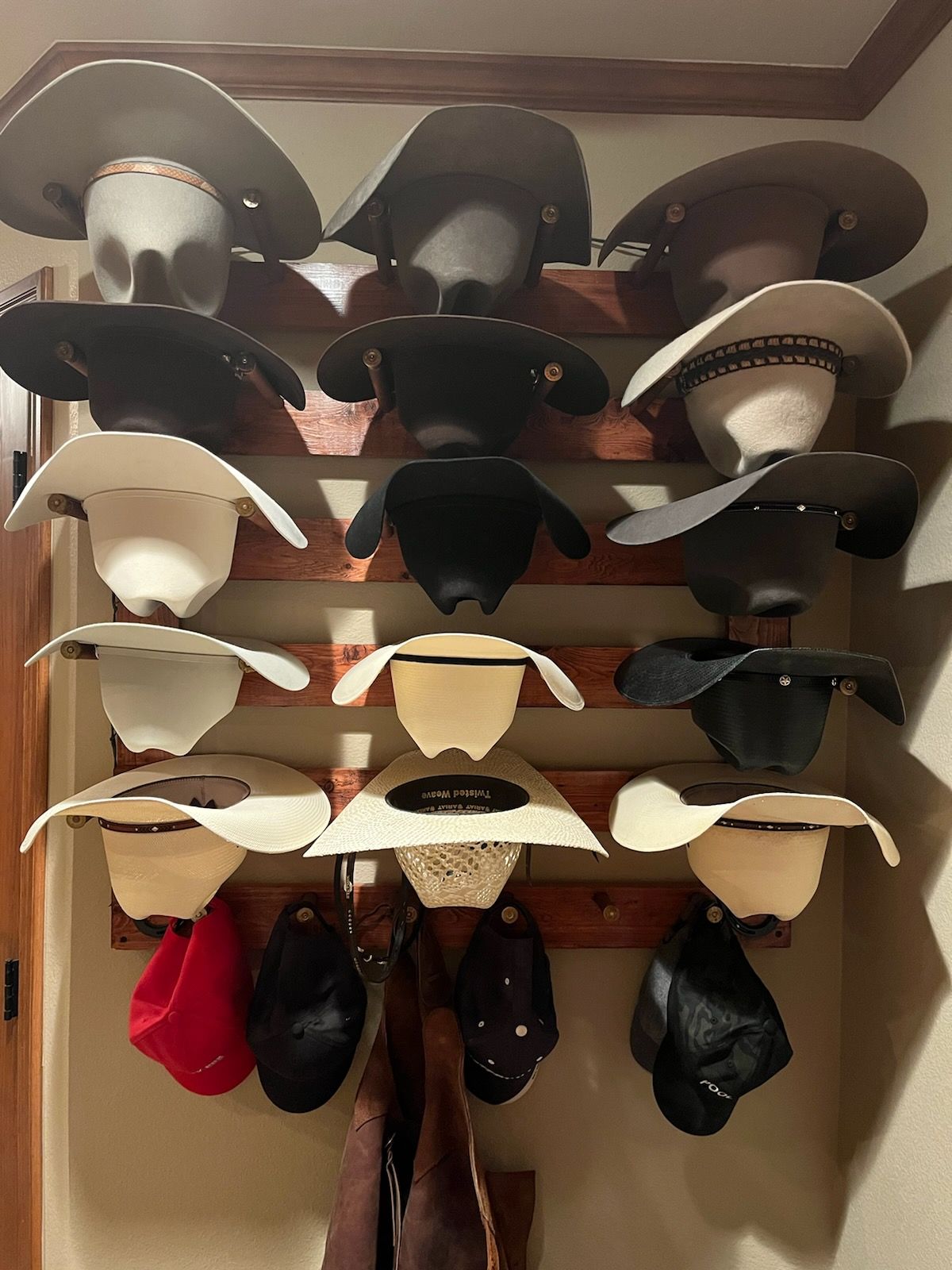 Cowboy hats displayed on a wooden rack, varying colors and styles.