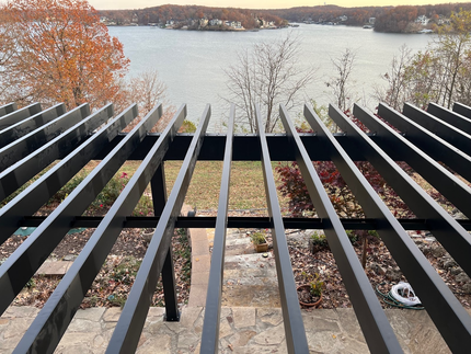Deck with a covered grill, trees, and a view of water and docks.