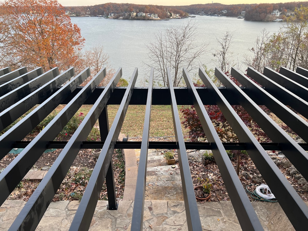 Deck with a covered grill, trees, and a view of water and docks.