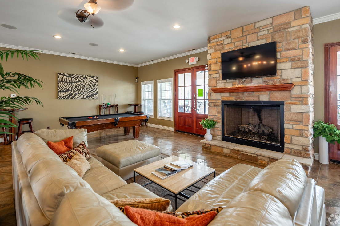 A living room with a couch , fireplace , pool table and television.