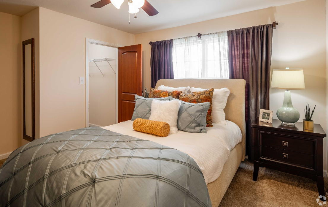 A bedroom with a bed , nightstand , lamp and ceiling fan.
