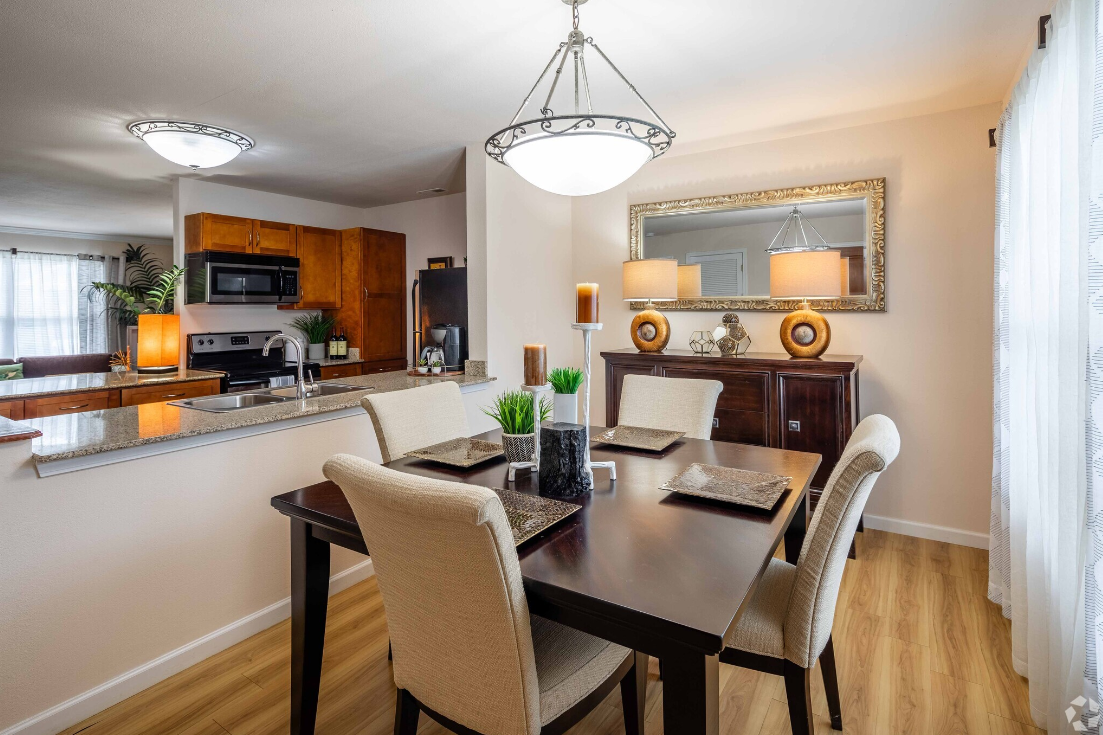 A dining room with a table and chairs and a mirror.