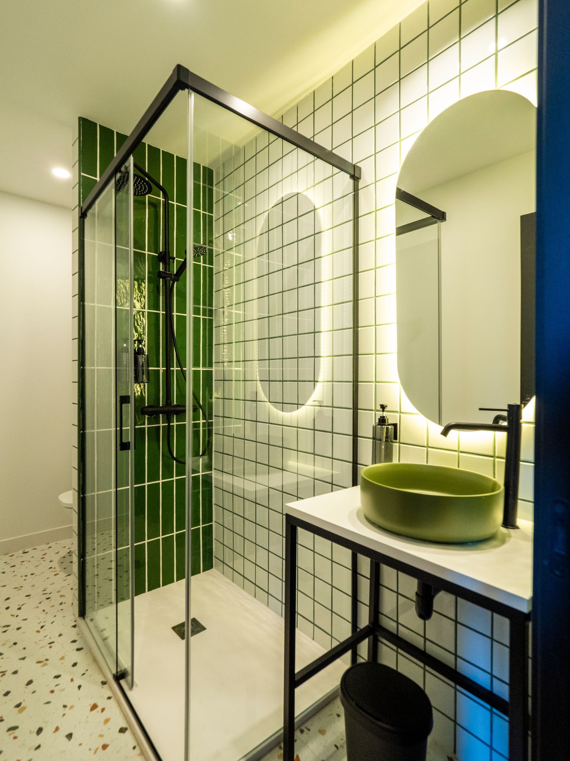 A bathroom with a sink and a shower with green tiles