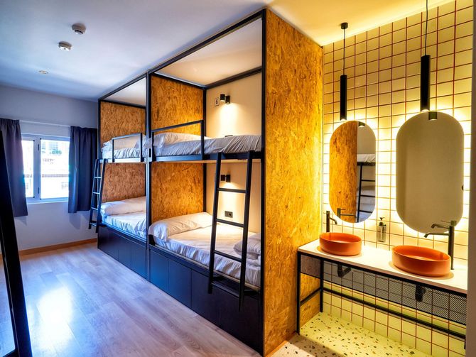 A bunk bed room with two sinks and two mirrors.