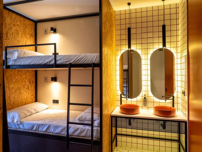 A bunk bed is next to a bathroom with two sinks.