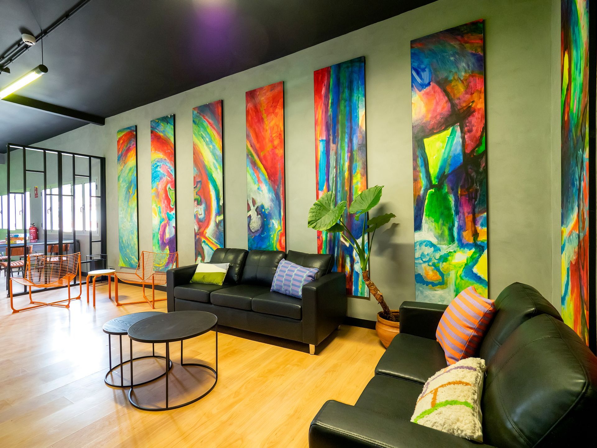 A living room with a couch , table , chairs and paintings on the walls.