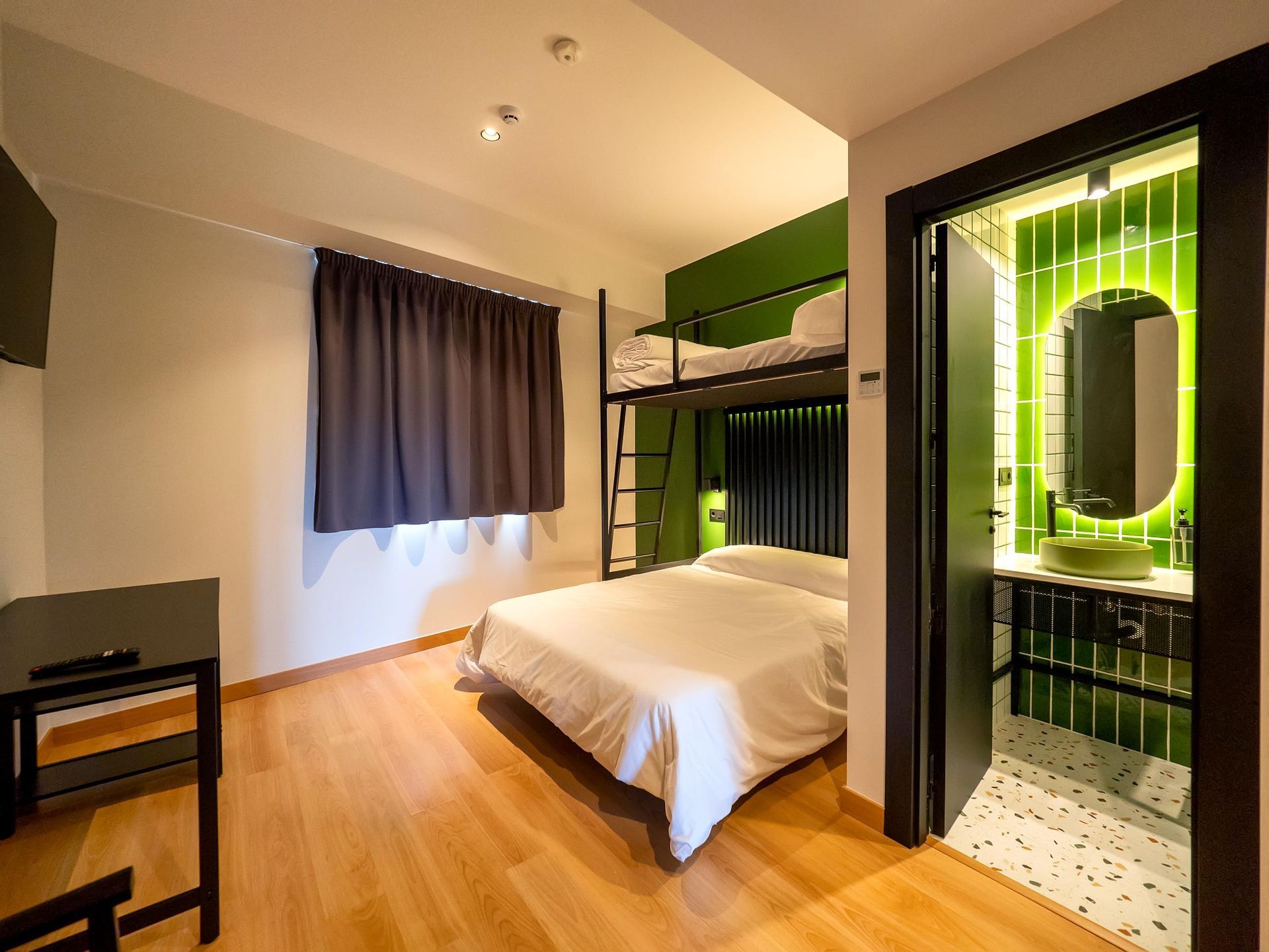 A hotel room with a bunk bed and a bathroom.