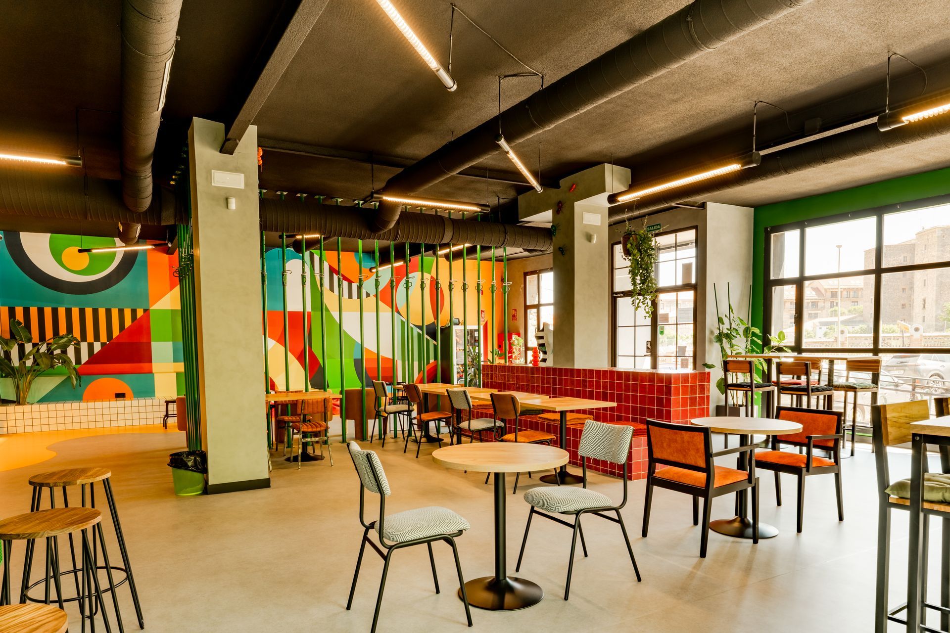 A large room with tables and chairs and a mural on the wall.