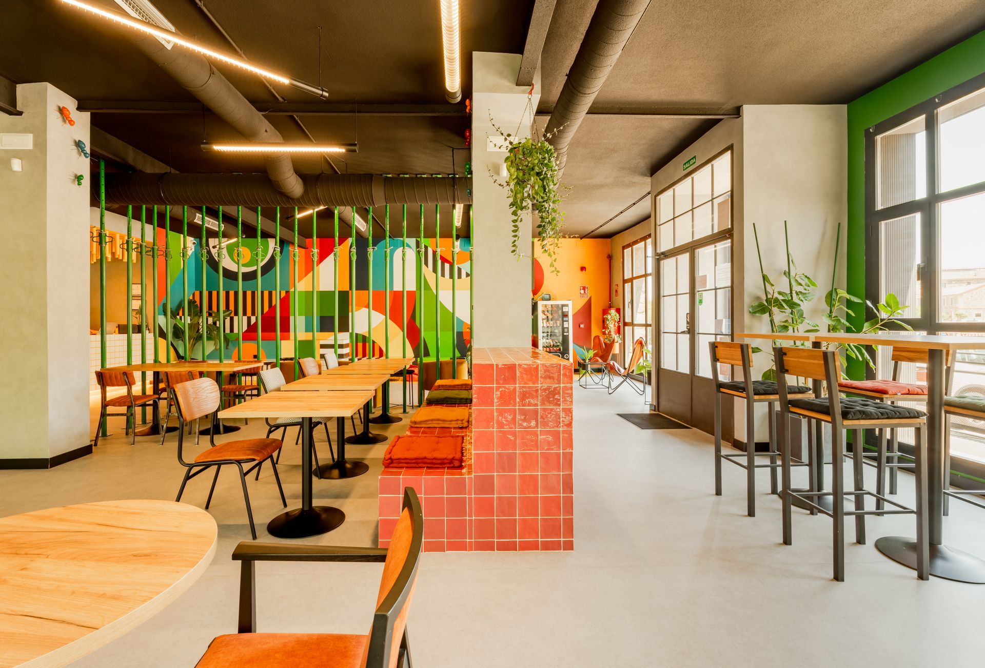 A common area with tables and chairs and a mural on the wall.