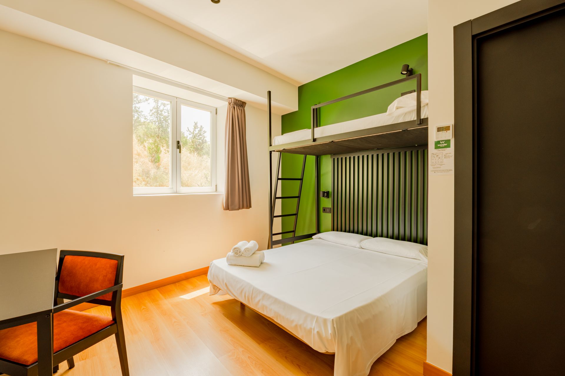 A hotel room with a bunk bed and a table and chairs.