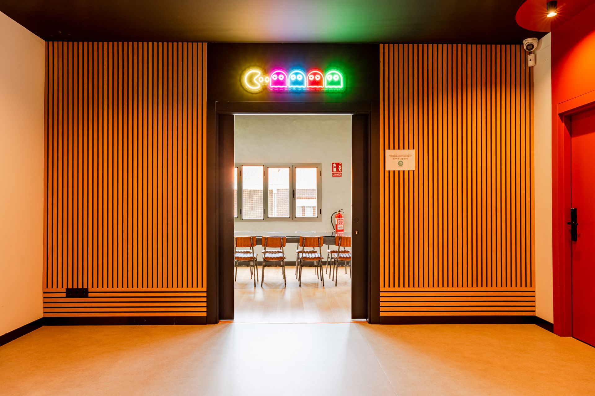 A hallway with a wooden wall and a neon sign.