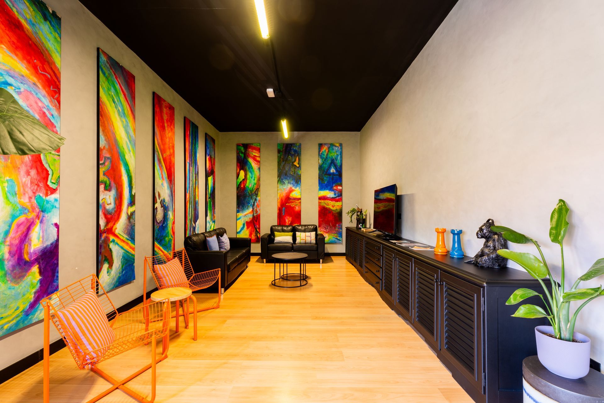 A living room filled with furniture and paintings on the walls.