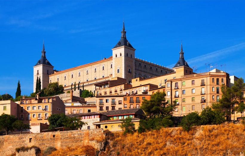 A large castle is sitting on top of a hill in the middle of a city.