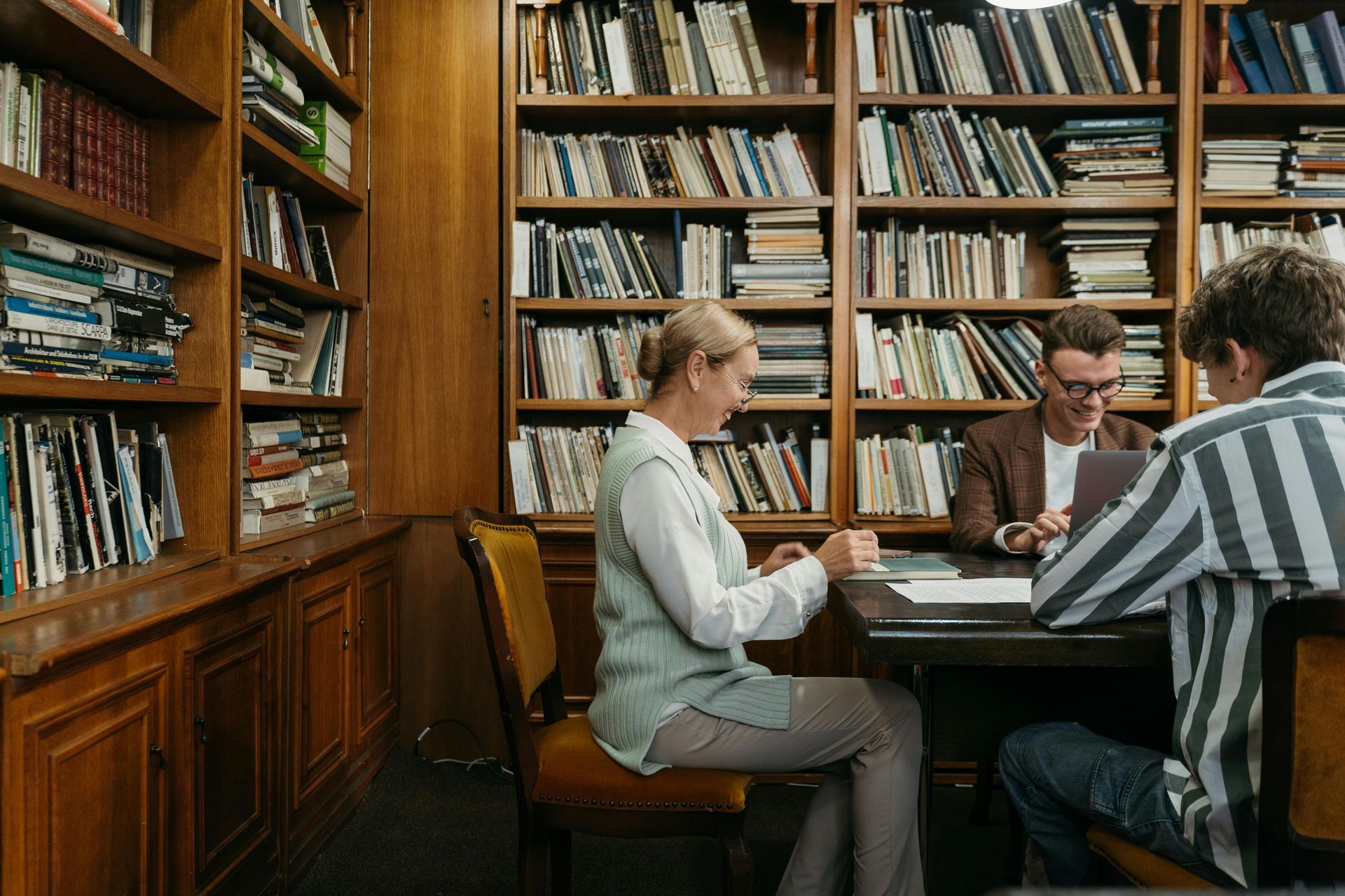 Group of people reading books at table in library
