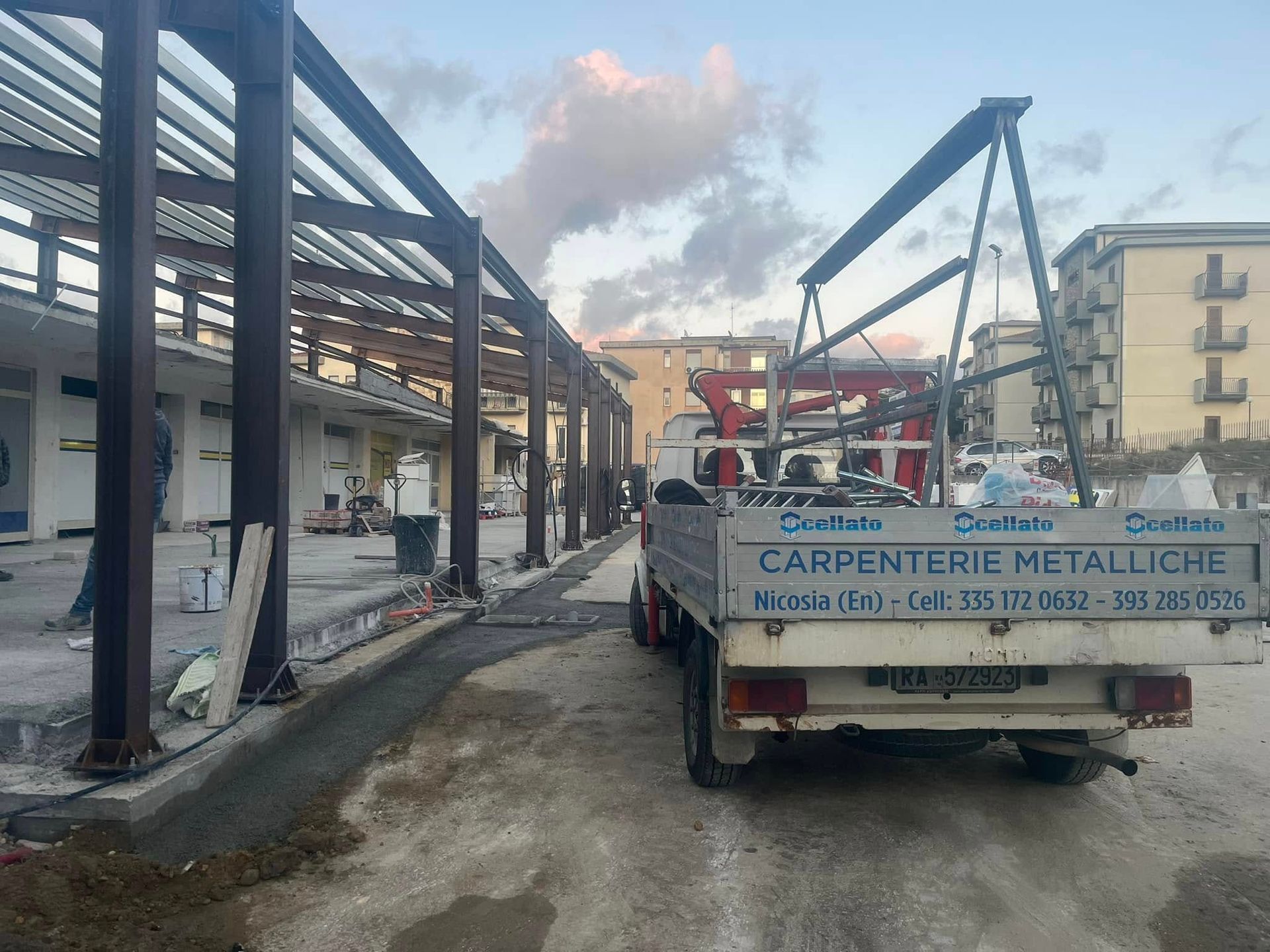 Cantiere con travi metalliche e un camion con la scritta 